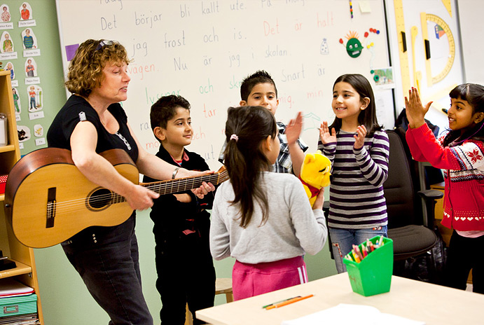 Lärare som spelar gitarr och elever i förskoleklass som dansar.
